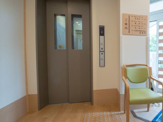 エレベーター前の椅子 玄関脇のエレベーター 快適に移動できるエレベーターが設置され、待ち時間もゆったり椅子で過ごせます。エレベーター前の案内表示も見やすくなっております。