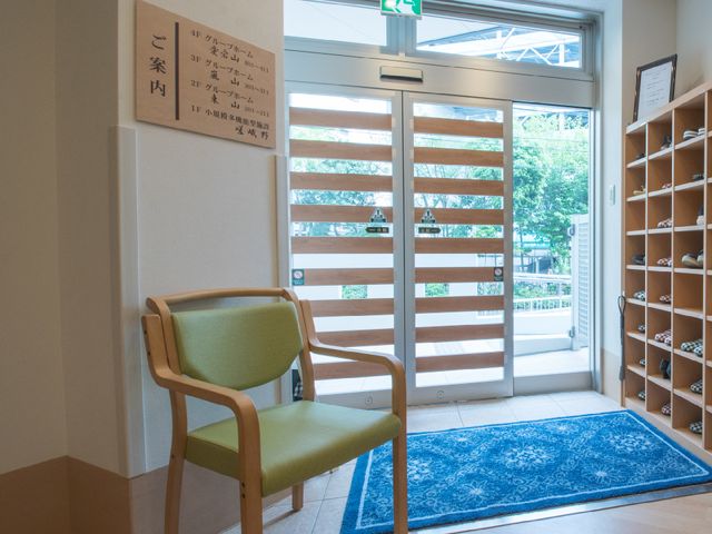 エントランスの椅子と案内板 玄関の自動ドア 美しい外観とは裏腹に、機能的で使いやすい入口が皆様をお迎えします。椅子に腰掛け、靴を履き替える際にも、安心してご利用いただけます。