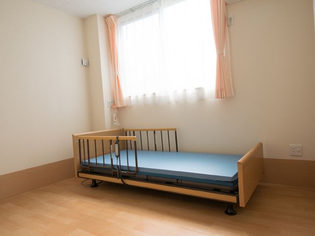 清潔な居室のベッド 室内とベット 日差しが優しく差し込む居室は、シンプルで使いやすいベッドが備えられ、落ち着いた空間を提供しています。