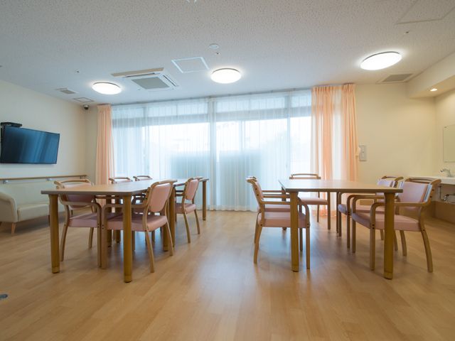 共用ダイニングスペース リビング・ダイニング1 ゆとりあるダイニングでは、職員の配慮と支援のもと食事の時間が安らぎのひとときになるよう工夫されています。木目調の家具が暖かみのある雰囲気を演出し、居心地のよい空間が広がっています。