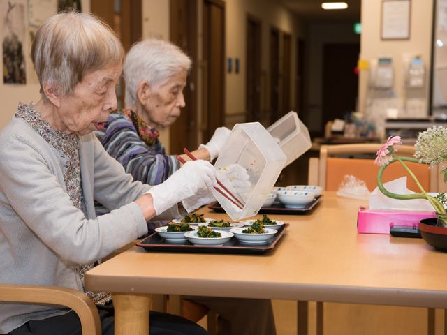 高齢者が食事をするダイニングルーム 調理補助 ゆったりとした食のひととき。参加者の方々が落ち着いた雰囲気の中で食事を楽しまれています。