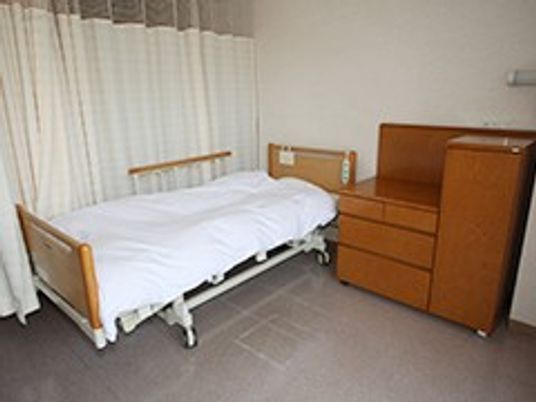 シンプルな居室のベッドと家具が並ぶ居室  