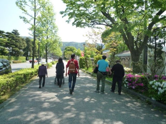 散歩する人々の背景 レクリエーション 緑豊かな中庭を歩く人々が映っており、様々な活動が楽しめる環境が整っています。