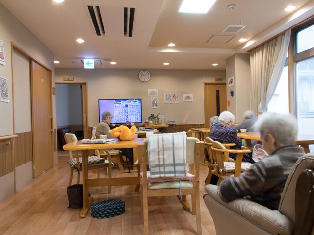 共有ラウンジの様子 食堂 ゆったりと寛げる椅子に座り、テレビを楽しむ方々の穏やかな共有空間です。お一人で読書をされている方もいらっしゃいます。
