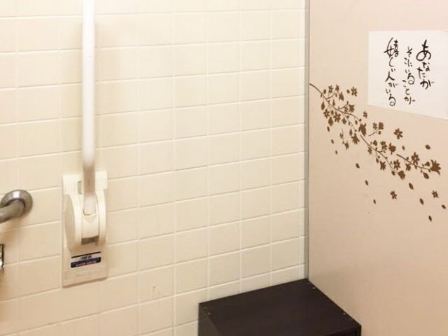 壁に装飾があるトイレ トイレ 壁には桜の装飾が施され、利用者に癒しの空間を提供しています。手すりも設置されています。
