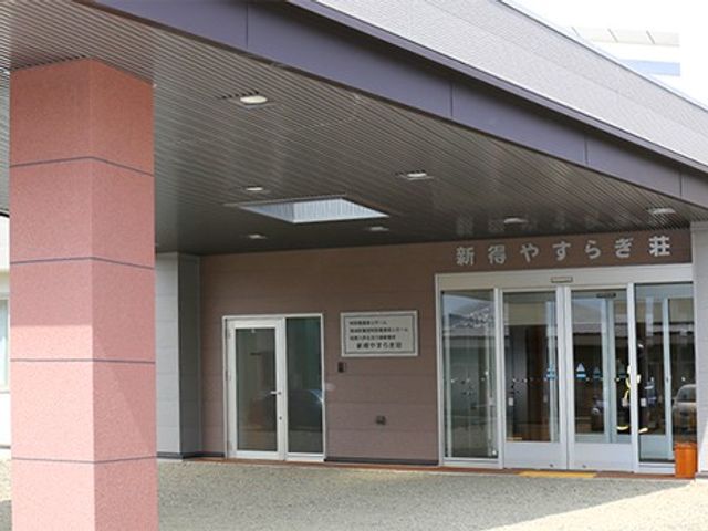 施設の正面玄関 外観   落ち着いた色合いの建物正面に、ガラス扉の出入口が設けられています。軒下が広く、雨の日も出入りしやすそうです。
