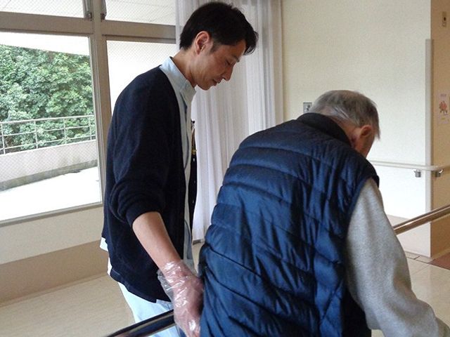 スタッフが手助けする廊下 廊下 自然光が差し込む明るい廊下で、スタッフがしっかりと利用者をサポートしています。