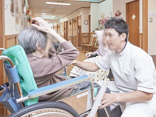 穏やかな交流の廊下 廊下 車椅子の入居者に寄り添う職員が、アットホームな雰囲気を醸し出しています。
