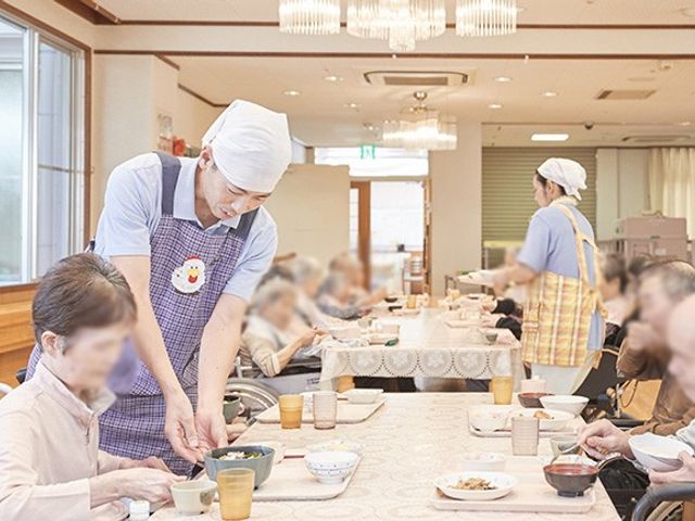 明るい食堂 食堂 広々とした明るい空間で、スタッフが利用者に食事を提供しています。快適な食事時間を過ごせます。