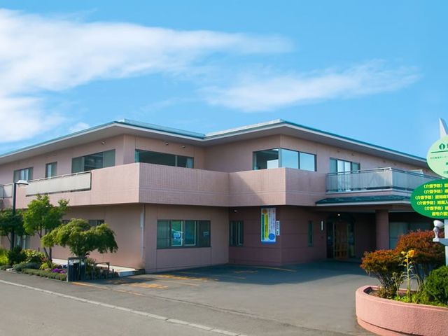 明るい外観の施設 外観   広い敷地に建つ2階建ての建物です。青空の下で、落ち着いた色合いの外観が見えます。