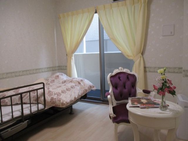 居室のベッドと椅子 トイレ ゆったりとした椅子が置かれた快適な居室です。ふかふかのベッドで、安らぎのひとときをお過ごしいただけます。