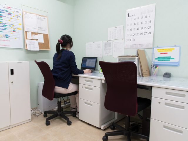 事務作業を行う職員 事務室 整然と配置されたオフィスで一生懸命仕事をする職員の姿から、職場の活気と丁寧な運営が伝わってきます。