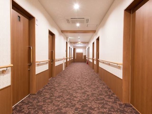 明るい廊下 廊下 両側に居室の扉が並ぶ、清潔感のあふれる廊下です。手すりが設置されており、安全に移動できる環境が整っています。