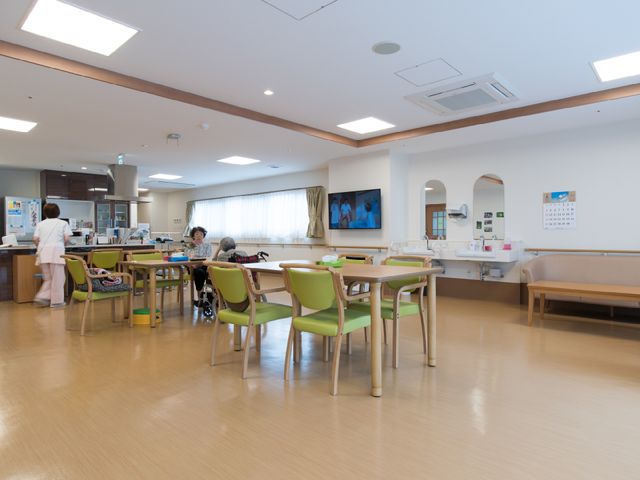 広々とした明るい食堂 リビングダイニング 広くて明るい居心地の良い食堂では、利用者様がゆったりとお食事を楽しんでいます。スタッフも温かいサポートを提供しており、和やかな雰囲気が伝わります。