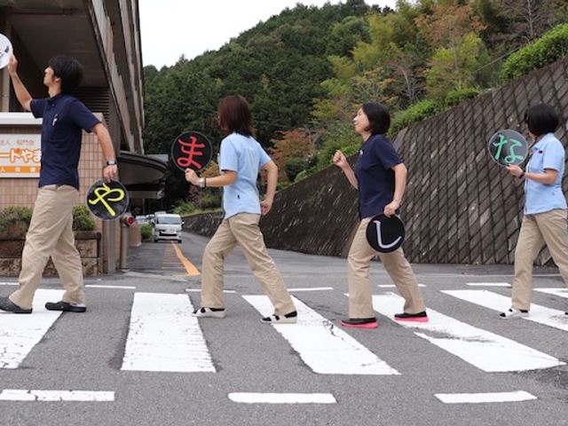 スタッフが横断歩道を渡る様子 スタッフイメージ スタッフが和気あいあいとした雰囲気で横断歩道を渡っています。楽しそうな職場環境が魅力です。
