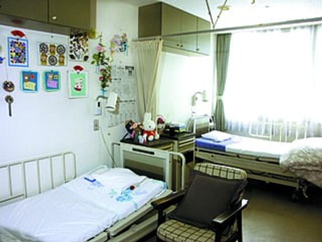 明るい居室のベッドまわり 居室   自然光が入る明るい居室です。ベッドや椅子がゆったり配置され、落ち着いて過ごしやすい雰囲気です。