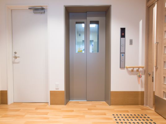 エレベーターと非常階段の扉が並んでいる。エレベーターには車椅子に座ったままでも押しやすいボタンが付いている。