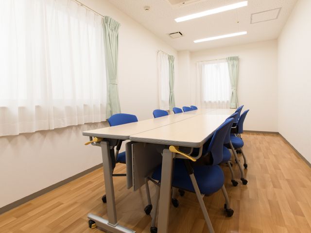 多目的に使える会議室 机と椅子のある部屋 床と椅子が色合いを合わせた明るく清潔感のある会議用スペースです。ゆったり配置された椅子が協議や研修に理想的な環境を提供しています。