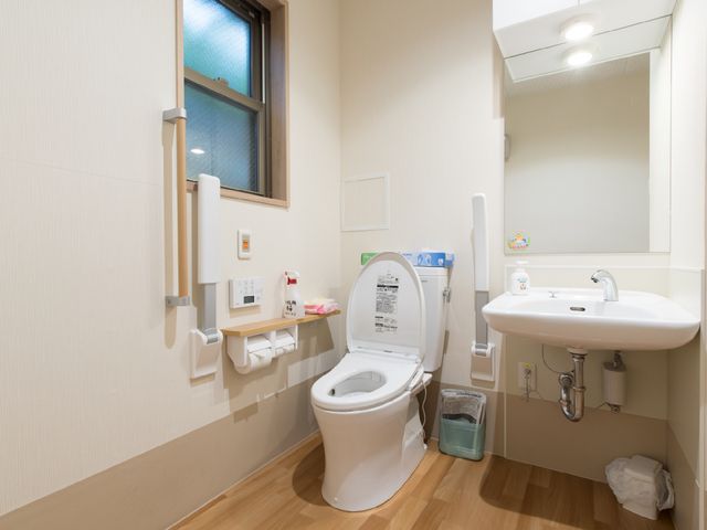 清潔なトイレ空間 トイレ 手すりや緊急コールが設置された安全な構造のトイレです。清潔感のある環境が保たれ、利用者の快適性を考慮した設計となっています。