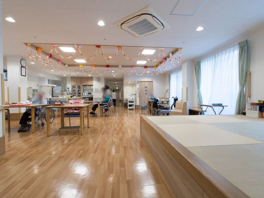 車椅子でも楽に移動が出来る広さ。腰を掛けるのに便利な高さの畳もある。天井の飾りがリビングを華やかにしている。