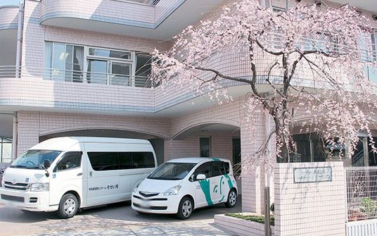 満開の桜と白い車が停まっている外観