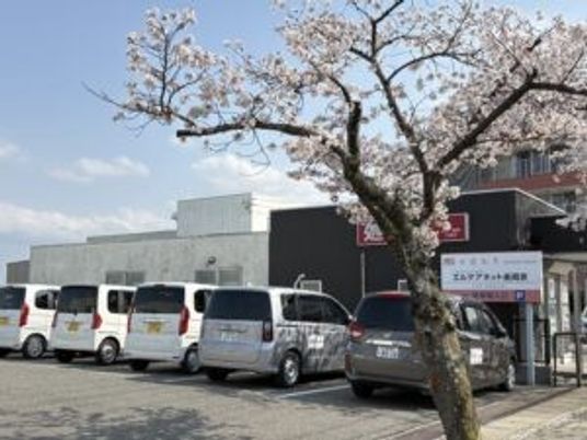 建物前の送迎車と桜の外観  