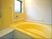 白色と黄色を基調としている。大きめの浴槽の周りには手すりが設置されている。小窓が１つあり明るい浴室である。