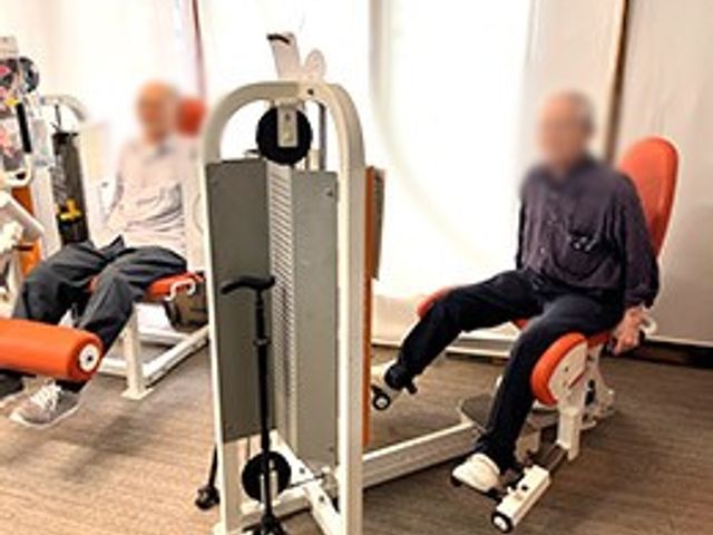 トレーニング機器の部屋 機能訓練室 自然光が入る明るいスペースで、利用者お二人がトレーニング機器を利用しながら健康維持に努めています。