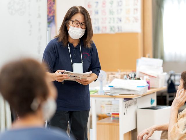 会議中のスタッフイメージ スタッフイメージ 明るい交流の場で、スタッフが利用者と共に資料を手にしています。意見交換には最適です。