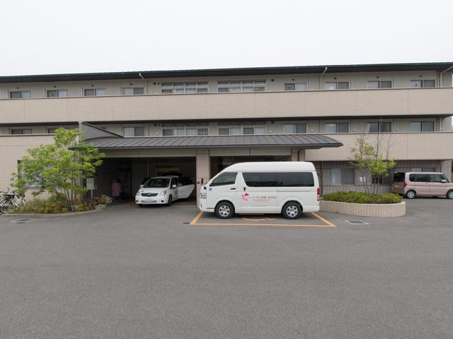 施設外観と駐車場 施設外観 広々とした駐車スペースが整備された、落ち着いた色調の建物です。静かな環境でのお仕事をご希望の方に適しています。