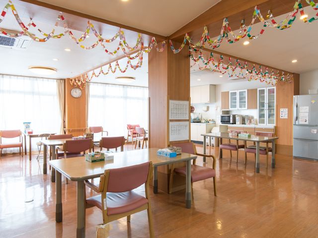 飾り付けられたダイニングルーム リビングダイニング1 カラフルな飾りが天井を彩るダイニングルームで、木のテーブルや椅子が温かみのある雰囲気を醸し出しています。窓からの自然光が入り、明るく開放的な空間です。