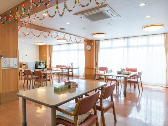 明るい共有ダイニングルーム リビング2 温かみのあるダイニングルームで、テレビを見ながらゆっくりとお食事いただけます。天井の彩りも心地よい空間を演出しています。