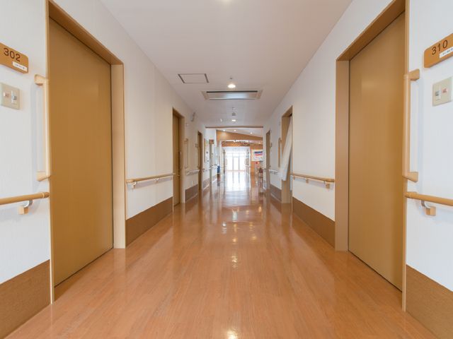 清潔な廊下 廊下1 木目調のフローリングが温かみのある廊下です。手すりが付いていて、安全に配慮された設計となっています。