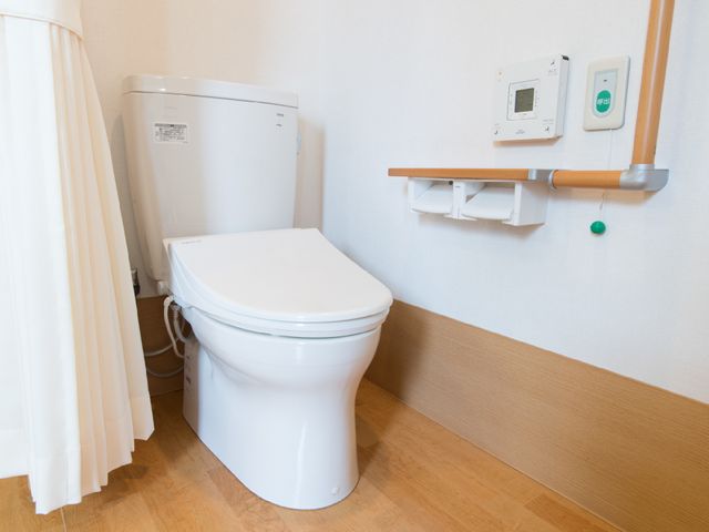 バリアフリートイレ設備 トイレ1 手すり付きで安全なトイレスペースです。非常時には、緑のボタンを押して通報が可能です。