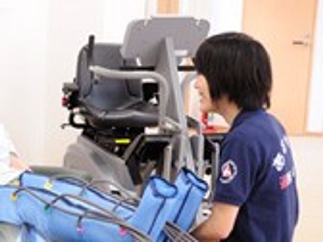 優しい交流の様子 機能訓練室 職員が親身に接する姿勢が伺えます。業務中に利用者との適切なコミュニケーションが重要です。