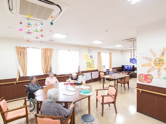 共有スペースの活動風景 休憩スペース 明るい光が満ちる多目的室で、利用者様が集い手工芸に興じる姿が見られます。心地よい交流の場を提供しており、日々の生活に潤いをもたらしています。