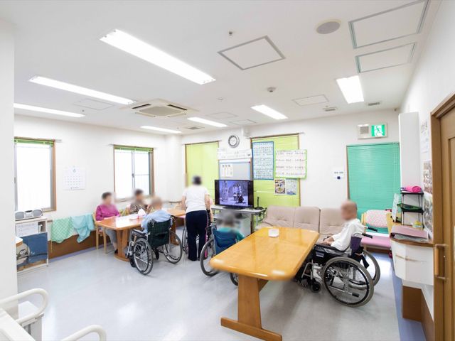 共有スペースの日常風景 共有スペース 居心地の良さが感じられる広々としたラウンジです。椅子に座る方や車椅子の方が、リラックスして過ごしている様子が伺えます。