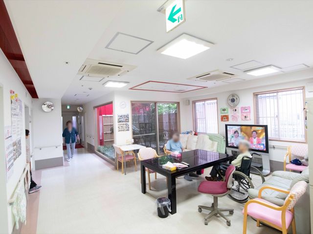 共有スペースの様子 共有スペース ゆとりあるラウンジでは、入居者がテレビを見たり、くつろいだりしています。バリアフリー設計で、車椅子の方も自由に動ける空間です。