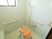サムネイル 白を基調とした清潔感のある浴室である。洗い場にはひじ掛けと背もたれのついたオレンジ色の椅子が置かれている。