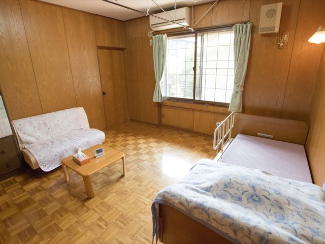 居室のソファとベッド 居室 木目調の温かみを感じる居室です。日当たりの良い窓辺で、ゆったりとした時間をお過ごしいただけます。