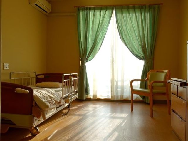 日差し入る居室 居室   大きな窓から光が差し込む、あたたかな雰囲気の居室です。ベッドと椅子があり、落ち着いて過ごしやすい空間に見えます。