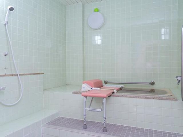 介助用浴室 浴室   明るいタイル張りの浴室です。浴槽のそばにシャワーチェアがあり、入浴介助に配慮したつくりです。