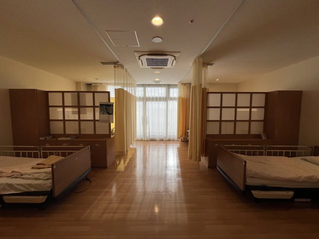 ベッドのある居室 居室 木目調の床と仕切りで落ち着いた雰囲気の空間で、プライバシーを配慮した設計になっています。