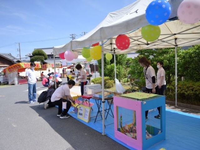 屋外の模擬店舗 外観   青空の下にテントが並び、出店の準備をする様子が見えます。利用者の交流や行事の場づくりがイメージしやすいです。