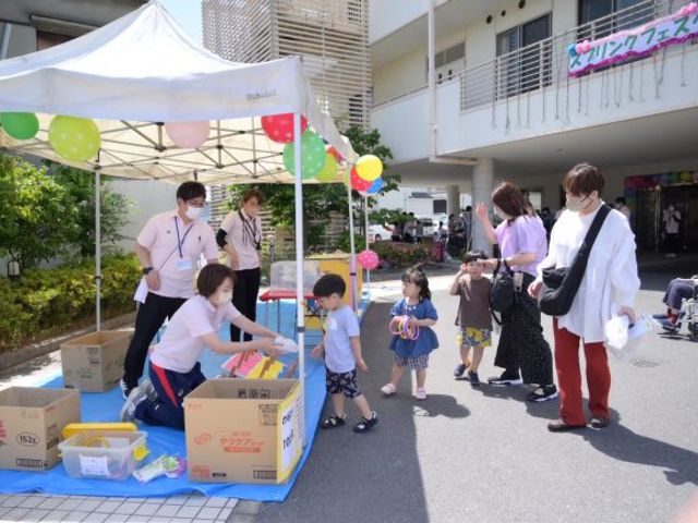 施設前のイベント会場 外観   施設の前で、テントを設置したイベントが開かれています。利用者や家族が集まり、にぎやかな交流の様子がうかがえます。