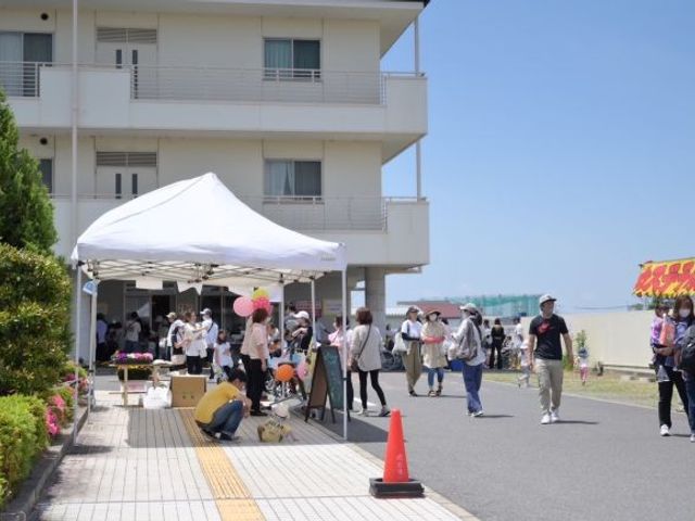 施設前の屋外イベント会場 外観   建物の前にテントが設けられ、屋外で催しが行われています。来場者の様子が見え、にぎやかな雰囲気です。