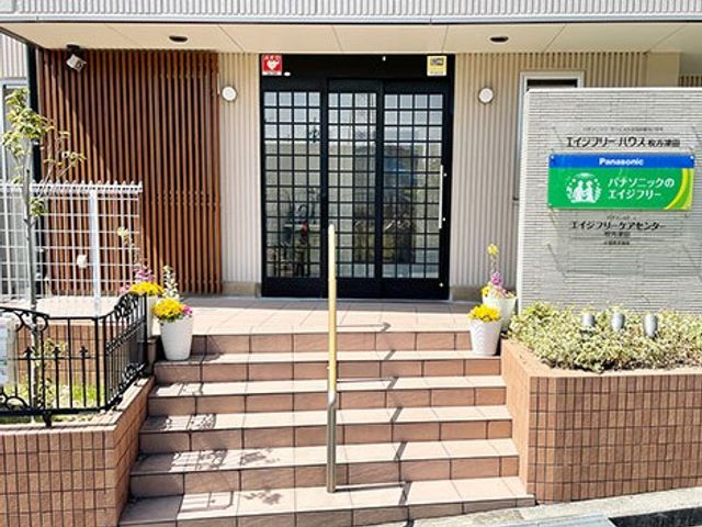 施設の玄関外観 外観   段差のあるアプローチと、中央の引き戸が印象的な玄関まわりです。看板が見え、施設の出入り口の雰囲気が伝わります。