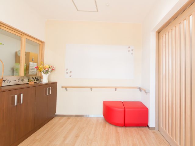 赤い椅子のある廊下 受付 清潔で明るいエントランスがお出迎え。赤い椅子がアクセントとなり、待ち時間も快適です。