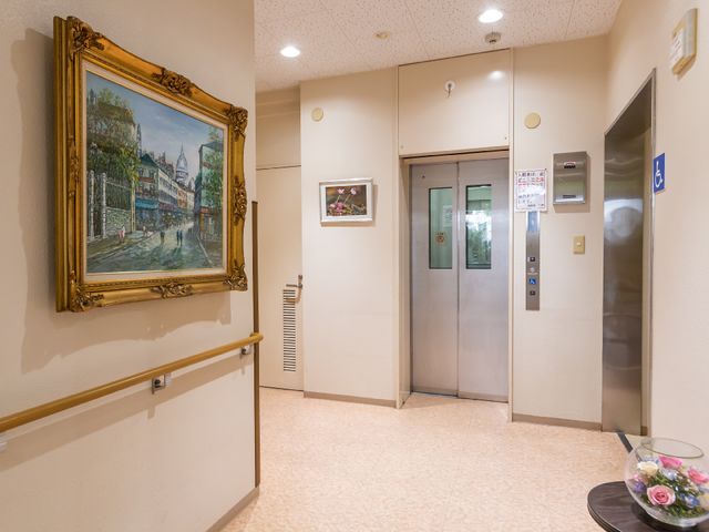 廊下にあるエレベーターと絵画 エレベーター 広々とした廊下には、利便性を考えた設計のエレベーターが備わっており、壁には美しい絵画が飾られています。