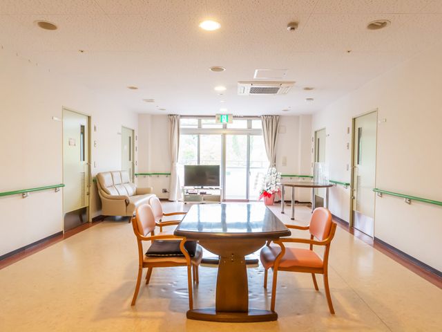 明るい居室 共有スペース 広々とした居室で、明かりをたっぷり取り入れる大きな窓があります。ソファやテーブルも配され、ゆったりとした時間を過ごせる空間です。